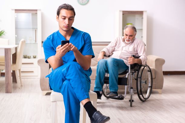 Nurse Neglects Elderly Patient - nurse on phone while patient is behind him in wheelchair